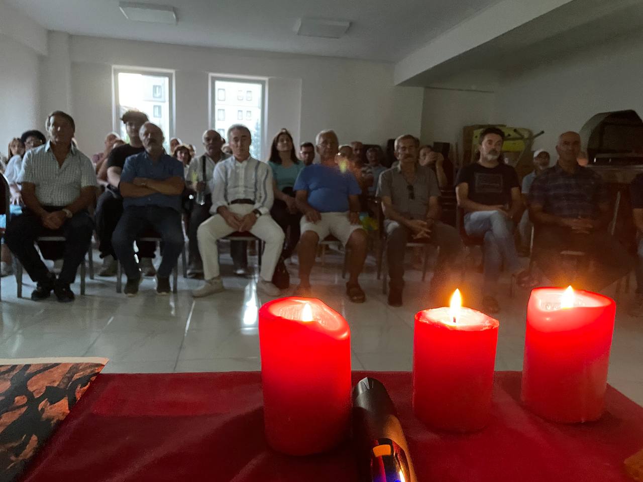 Yanan üç çıra ve gösterimi izleyen canlar